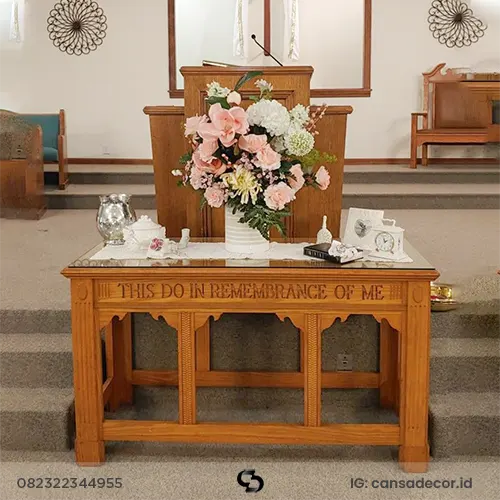 Meja altar perjamuan kudus minimalis dari kayu jati dengan ukiran tulisan rohani di bagian panel depan.